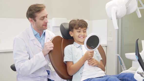 Lovely Boy Checking Out His Healthy Teeth in the Mirror After Dental Examination