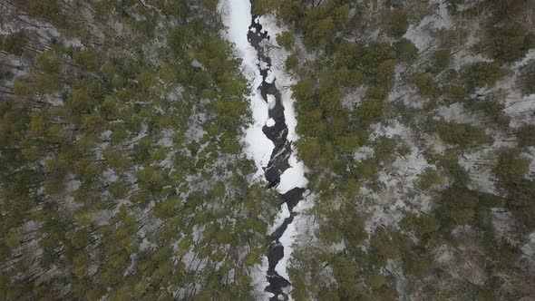 Top down drone shot moving down on snowy river in winter