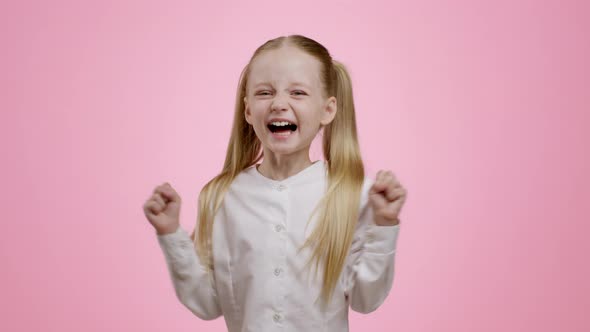 Cute Happy Little Girl with Ponytails Enjoying Success or Present Laughing and Gesturing Pink