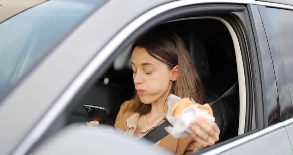 Woman Typing on a Smart Phone While Having a Snack in a Vehicle