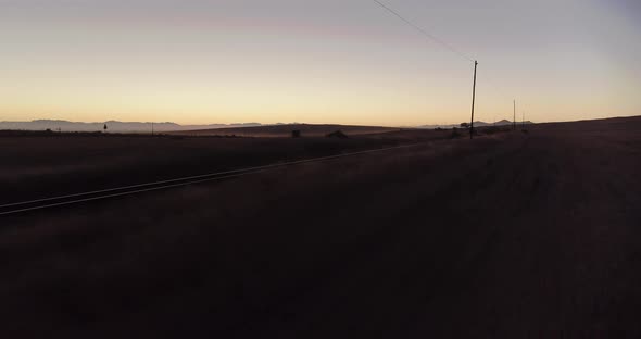 4K Drone shot revealing light reflecting on train tracks in the dark bush before sunrise