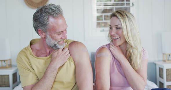 Happy caucasian mature couple showing plaster on arm where they were vaccinated against coronavirus