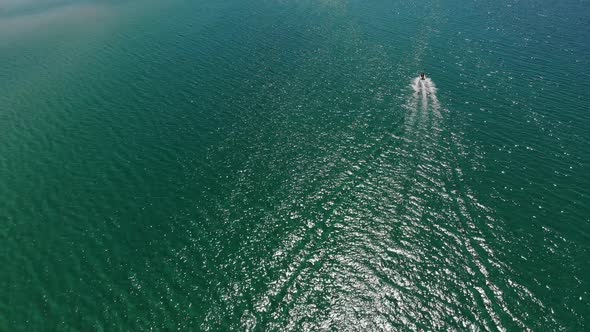 Aerial View of a Motor Boat Sailing Across the Clear Turquoise Sea on a Sunny Day