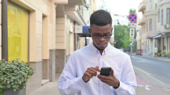 Walking African Man Using Smartphone