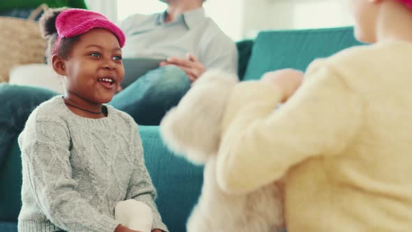 Smiling multinational sisters wearing sleep masks playing with toys