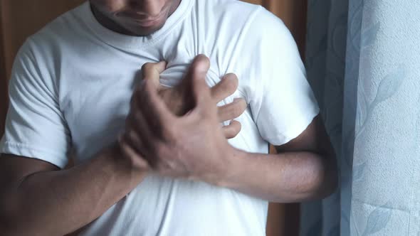 Young Man Suffering Pain in Heart and Holding Chest with Hand