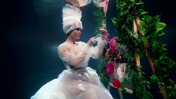 Romantic and Strange Dream of Underwater Floral Fairy Lady in White Gown is Sewing Flowers