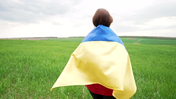 Unrecognizable Ukrainian Woman Walking with National Flag in Green Field