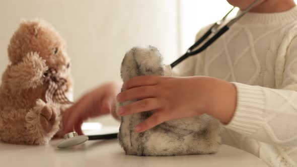 Cute little boy playing doctor at home and curing plush toy