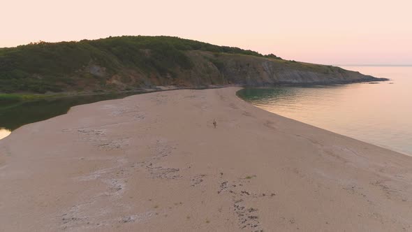 Couple Walking on Narrow Strip of Sand Between River and Sea at Sunset at Sinemorets, Bulgaria