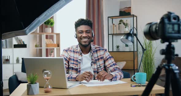 Black-Skinned Guy in Headphones with Mic Sitting in front of Camera