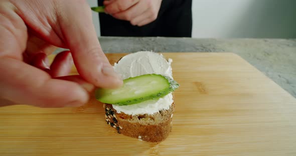 A Chef in a Kitchen Spreads Soft Cheese on Toasted Toast