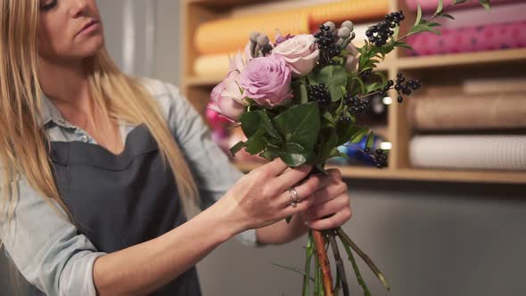 Young Female Blonde Florist Arranging Modern Bouquet and Looking How the Flowers are Combined