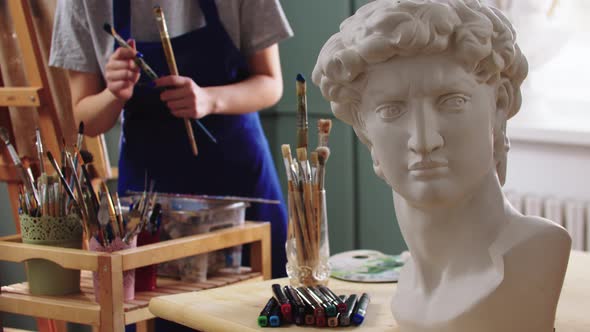 A Woman Artist Choosing Brushes From the Jar  Marble Sculpture on the Foreground