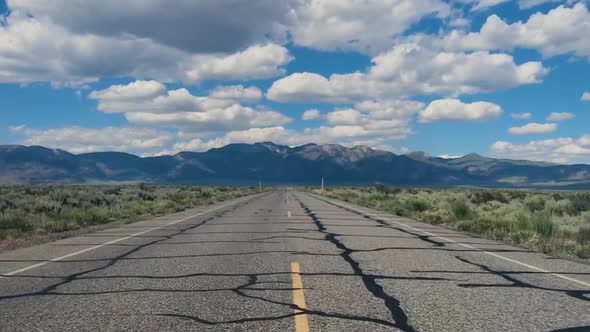 Small Asphalt Road Surrounded By Desert with Clouded Blue Sky.