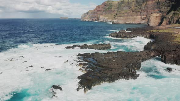 Aerial View of the Massive Foamy Waves Splashing Against Steep Coastline