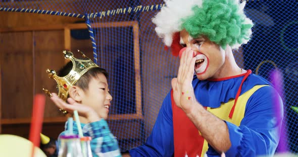 Clown giving high five to boy during birthday party 4k