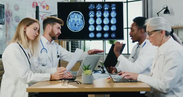 Team of Neurologists Working Together in Modern Medical Room with Medical Reports