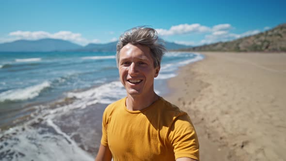 Close Up Selfie Portrait of Happy Middle Aged Greyhead Man at Sea Coast Enjoys Sunny Day on
