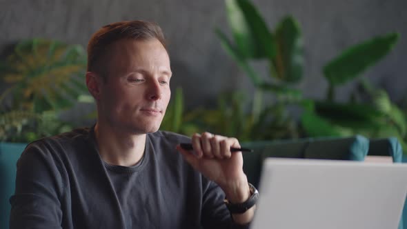 Thoughtful Serious Young Man Student Writer Sit at Home Office Desk with Laptop Thinking of