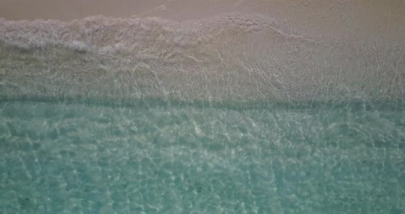 Wide angle flying tourism shot of a sunshine white sandy paradise beach and blue water background