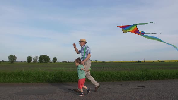 Grandpa with Boy Running with Kite in Countryside