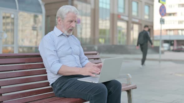 Old Man Reacting to Loss on Laptop While Sitting Outdoor on Bench