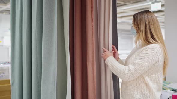 Woman in a Protective Mask Closeup in the Store Chooses Home Textiles Curtains