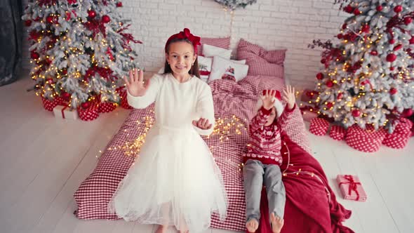 Portrait of Attractive Cute Kids Wearing Christmas Wear Falling Together on Bed in Apartment