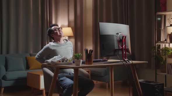 Asian Male Footwear Designer Having A Backache While Working On A Desktop Computer At Home