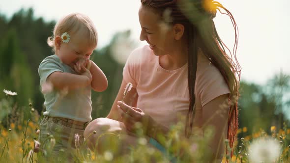 Mom with a child are sitting in a clearing or park. Parenting Maternity Joy Family Concept.