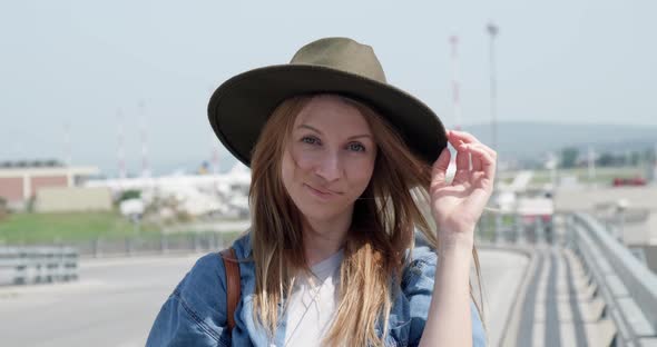 Happy tourist woman outside airport smiling and looking at camera.