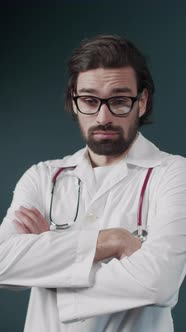 Portrait of Confident Young Medical Doctor in Glasses and with Statoskope on Green Background