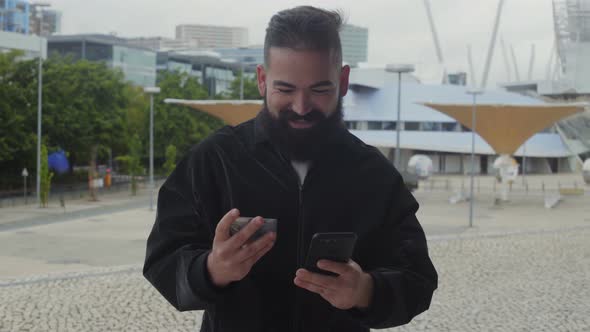 Smiling Bearded Man Typing Card Number on Smartphone Outdoor