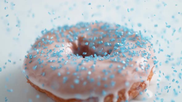 Sprinkling sugar on frosted doughnut. Slow Motion.
