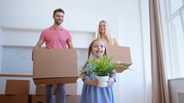 Funny little preschooler daughter looks at parents walking along new apartment