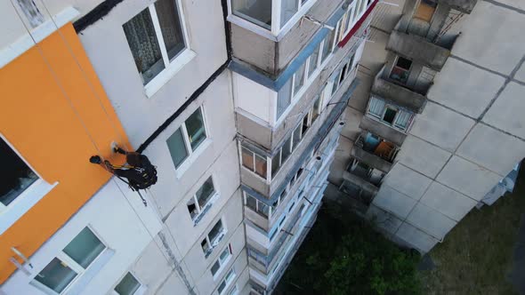 Painting and Decorating Buildings. Worker on a Construction Site of a High-rise Building. Dangerous