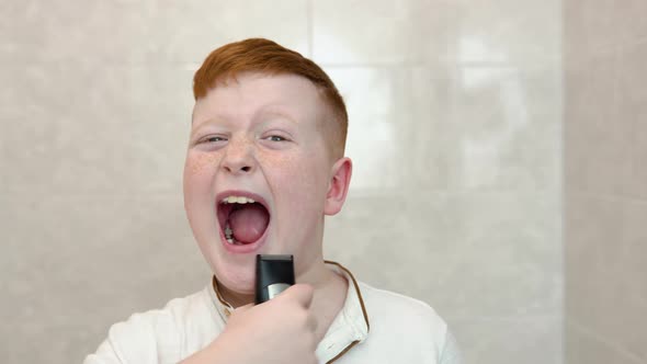 Little Boy is Shaving His Face with Electric Razor in the Bathroom