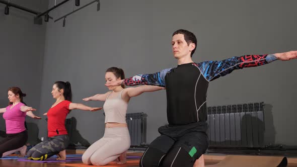 Group of Beginners in Coloured Sports Suits Stretches Hands