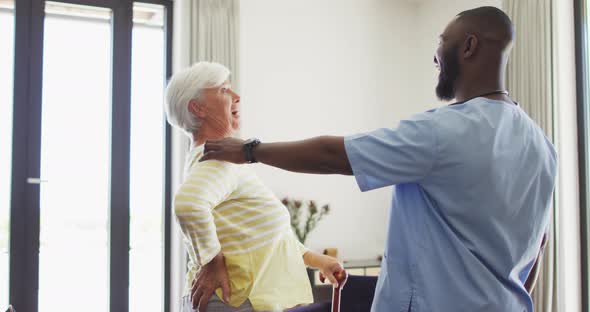 Video of happy african american male doctor supporting caucasian senior woman