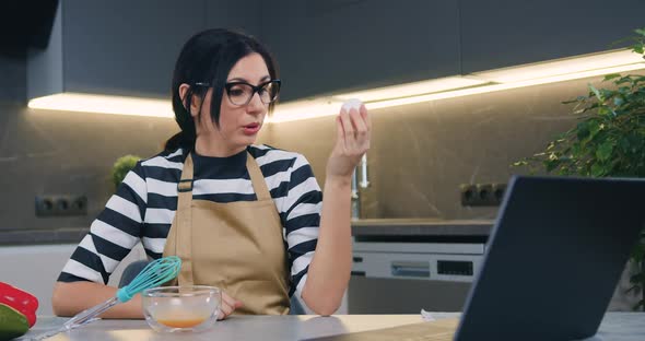 Woman in Glasses Has Online Video Chat with Friend and Telling How to Prepare Ingredients