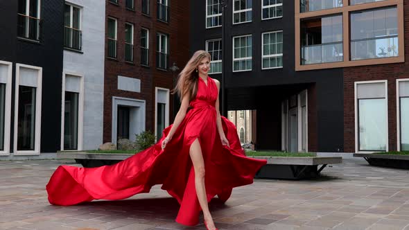 Young Gorgeous Woman in Long Red Dress Walking in the City