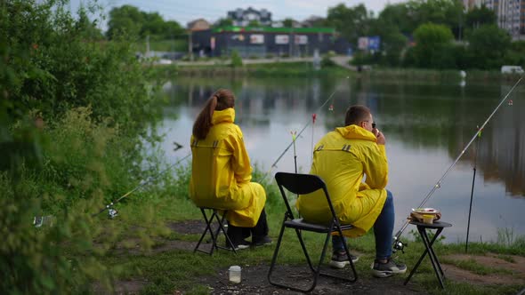 Positive Couple Fishing Outdoors in Urban Park Sitting on River Bank Talking in Slow Motion