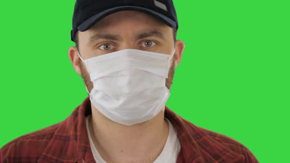 Man in Black Baseball Cap with a Medical Mask on His Face on a Green Screen, Chroma Key.