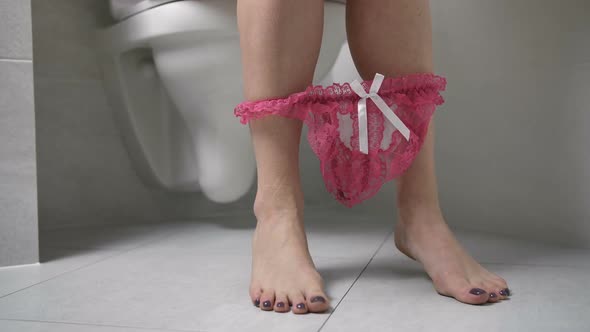Legs of Woman on Toilet Pulling Down Knickers