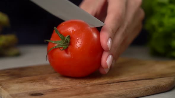 Woman cutting red tomato in kitchen