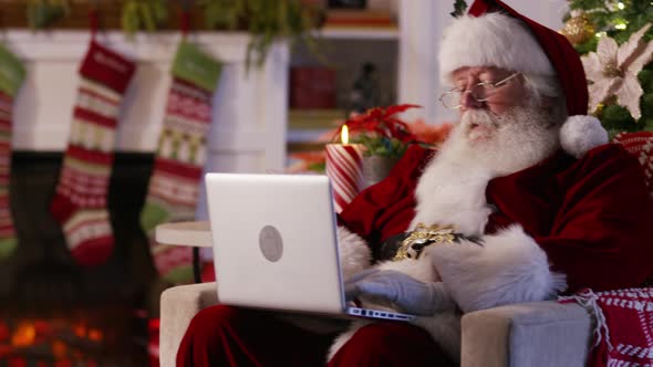 Santa Claus using laptop in living room alt