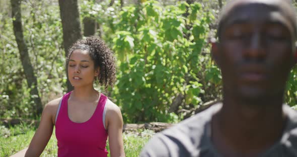 Diverse couple practicing yoga and meditating in countryside