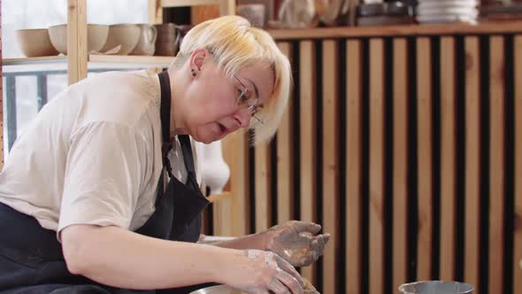 An Elderly Woman Using a Sponge on Wet Clay Plate on the Pottery Wheel