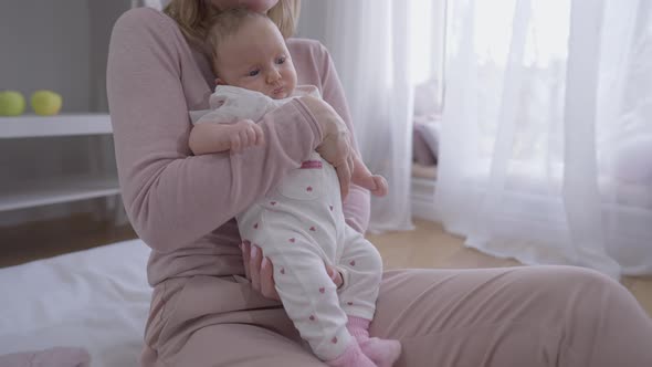 Wide Shot Curios Newborn Baby Girl in Hands of Unrecognizable Woman